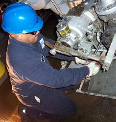 Plant worker with blue hard hat working on a machine